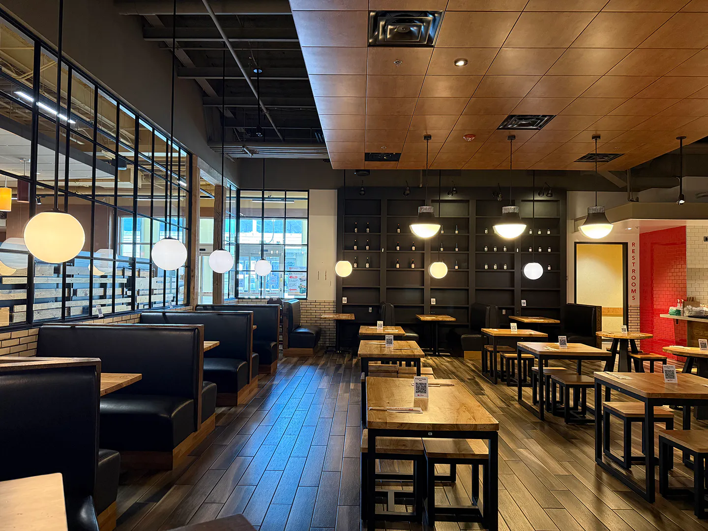 Modern restaurant dining room with wood tables and warm pendant lights at Kung Fu Noodle, a Chinese Noodle Restaurant in Natick